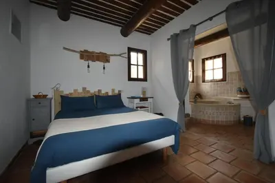 a bedroom with a blue and white bed and a tub at Les Chambres du Luberon & Table d'hôtes in Lauris