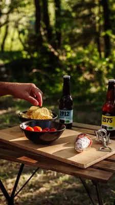 a table with two bottles of beer and a bowl of chips at Homnest - Infusion Provençale - Lisière & Ocres in Viens