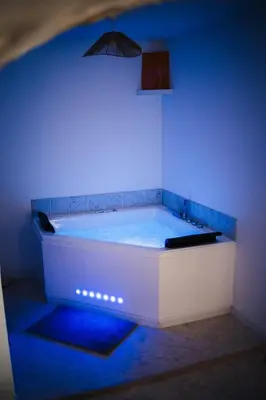 a bath tub in a room with blue lighting at Évasion grecque en duo Suite balnéo Wifi in Carpentras