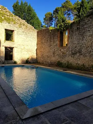 a swimming pool in front of a brick wall at Au pied du Colorado Provencal in Rustrel