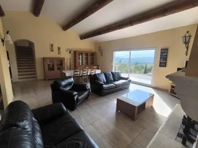a living room with black leather furniture and a table at La Colline sous les etoiles in Lincel