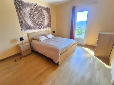 a bedroom with a bed and a large window at La Colline sous les etoiles in Lincel