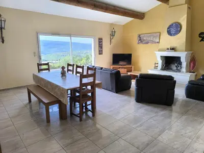 a living room with a table and chairs and a fireplace at La Colline sous les etoiles in Lincel