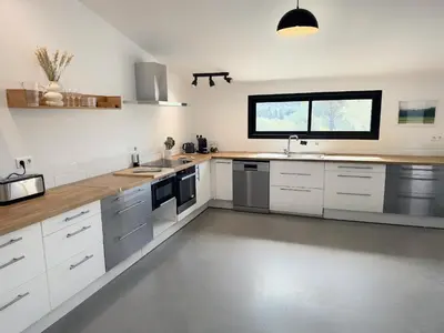 a large kitchen with white cabinets and a window at Villa des Glauges in Eyguières