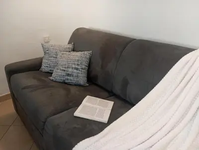 a book sitting on a brown couch with pillows at Evasion Aixoise logement T2 au Centre historique in Aix-en-Provence