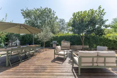 a patio with tables and chairs and an umbrella at Villa le Trèfle with pool in Velaux