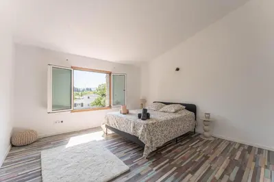a white bedroom with a bed and a window at Villa le Trèfle with pool in Velaux