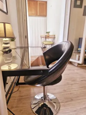 a black chair sitting next to a glass table at Charmant appart central avec Terrasse & Clim in Aix-en-Provence