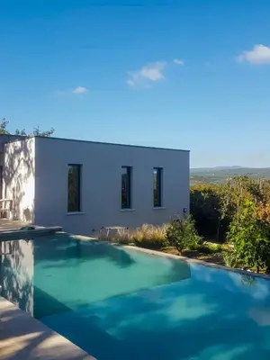 a swimming pool in front of a white house at Contemporary Villa With Pool In Céreste-En-Luberon in Céreste