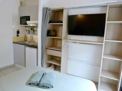 a living room with a tv and a kitchen at Le Clos d'AIX Studio 113 in Aix-en-Provence