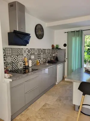 a kitchen with white cabinets and a clock on the wall at Maison BRIALI avec Jacuzzi espace détente in Aubignan