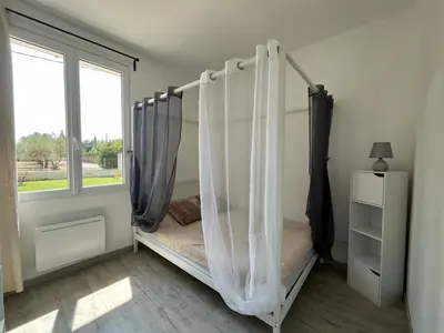 a bedroom with a bed with a mosquito net at Maison BRIALI avec Jacuzzi espace détente in Aubignan