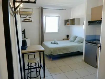 a bedroom with a bed and a table and a kitchen at Le Clos d'AIX Studio 304 Parking in Aix-en-Provence