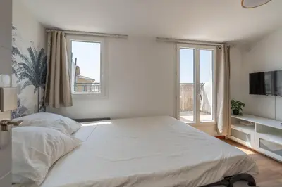 a bedroom with a large white bed and windows at Studio climatisé avec terrasse, 5ème étage sans ascenseur in Aix-en-Provence