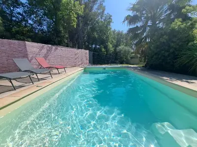 two chairs and a swimming pool with blue water at Villa Eguilles, ensoleillée, piscine à 10 mn d' Aix en Provence in Éguilles