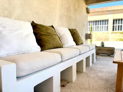 a white bench with pillows on a patio at Maison Poumo, Piscine, clim & padel privé,12 pers in LʼIsle-sur-la-Sorgue