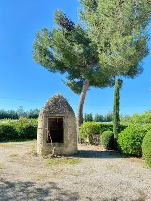 a stone shelter with a tree in a field at Maison Poumo, Piscine, clim & padel privé,12 pers in LʼIsle-sur-la-Sorgue