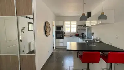 a kitchen with a black counter and red chairs at Maison climatisée avec jardin in Caumont-sur-Durance