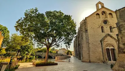 an old brick church with a tree next to it at Cosy & Cocooning in Le Thor