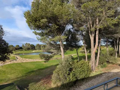 a view of a golf course with trees and a lake at Golf apartment in Saumane-de-Vaucluse