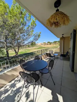 a patio with tables and chairs on a balcony at Golf apartment in Saumane-de-Vaucluse
