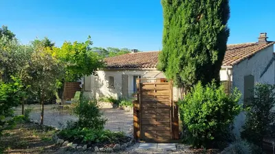 a house with a wooden gate in a garden at Gîte Le Verger Paisible in Malemort-du-Comtat