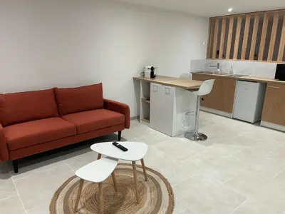 a living room with a red couch and a kitchen at Suite jacuzzi in Aix-en-Provence