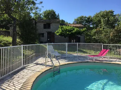 a swimming pool with a white fence and a chair at Cabanon provençal en pierre entouré de lavandes in Vachères