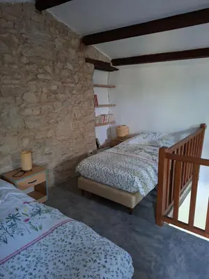 a bedroom with two beds and a stone wall at Cabanon provençal en pierre entouré de lavandes in Vachères
