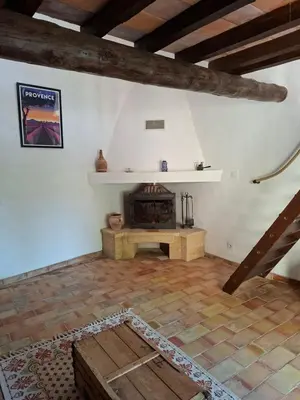 a living room with a fireplace and a wooden floor at Cabanon provençal en pierre entouré de lavandes in Vachères
