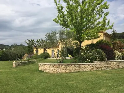 a house with a stone wall and a tree at La bergerie in Cadenet