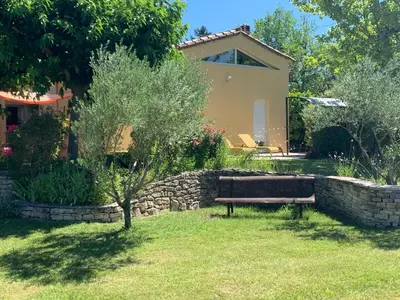 a bench in a yard next to a stone wall at La bergerie in Cadenet