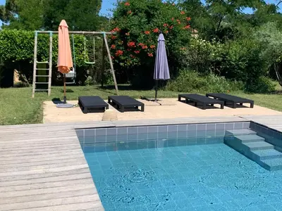 a swimming pool with two umbrellas and a ladder and a swing at La bergerie in Cadenet