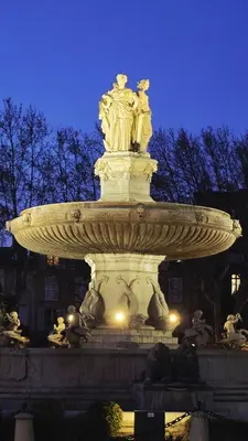 a fountain in the middle of a city at night at Appartement cosy et silencieux avec salon & chambre & mezzanine - 3 couchages - en plein centre historique et proche transports in Aix-en-Provence