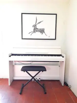a white piano with a picture on the wall at La Cachette centre historique village in Roussillon