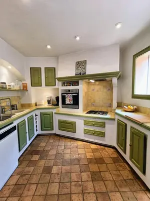 a large kitchen with green cabinets and a tile floor at Au coeur des ocres in Roussillon