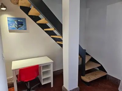 a room with a desk and a staircase with a red chair at Le nid douillet in Pertuis