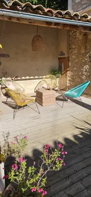 a patio with two chairs and a table and flowers at Le nid douillet in Pertuis