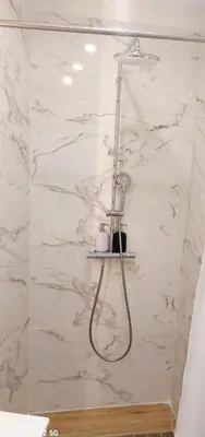 a shower in a bathroom with white marble walls at Studio MAREVA in Cavaillon