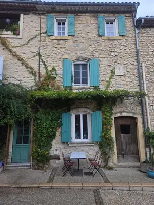 an old stone house with blue shutters and two chairs at Appartement Gîte d'Etape Vitrolles en Luberon in Vitrolles-en-Luberon