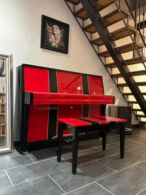 a red piano with a bench in a room at Maison Hélène Piano in La Tour-dʼAigues