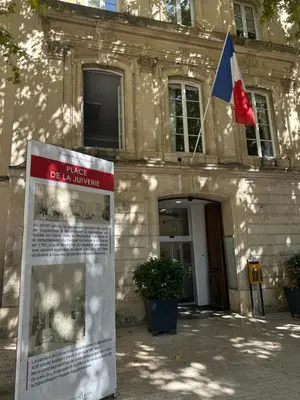 a sign in front of a building with a flag at CARPENTRAS 2ème étage BEL APPARTEMENT au CENTRE VILLE in Carpentras