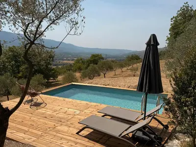 an umbrella and chairs next to a swimming pool at Bastidon avec vue et piscine au coeur du Luberon in Céreste