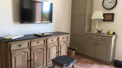 a room with a tv on the wall and a table at Les Carrairades in Mollégès
