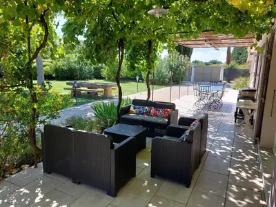 a patio with couches and tables under a pergola at Les Carrairades in Mollégès