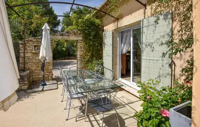 a patio with a glass table and an umbrella at Maison Avec Piscine Privée in Lacoste