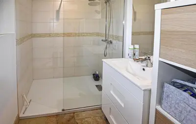 a white bathroom with a shower and a sink at Maison Avec Piscine Privée in Lacoste