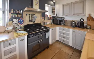 a kitchen with a stove and white cabinets at Maison Avec Piscine Privée in Lacoste