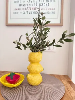 a yellow vase with a plant in it on a table at Cozy studio with air conditioning & pool & parking in Aix-en-Provence
