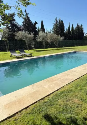 a swimming pool with two benches in the grass at Escapade Provençale 5 in Aix-en-Provence